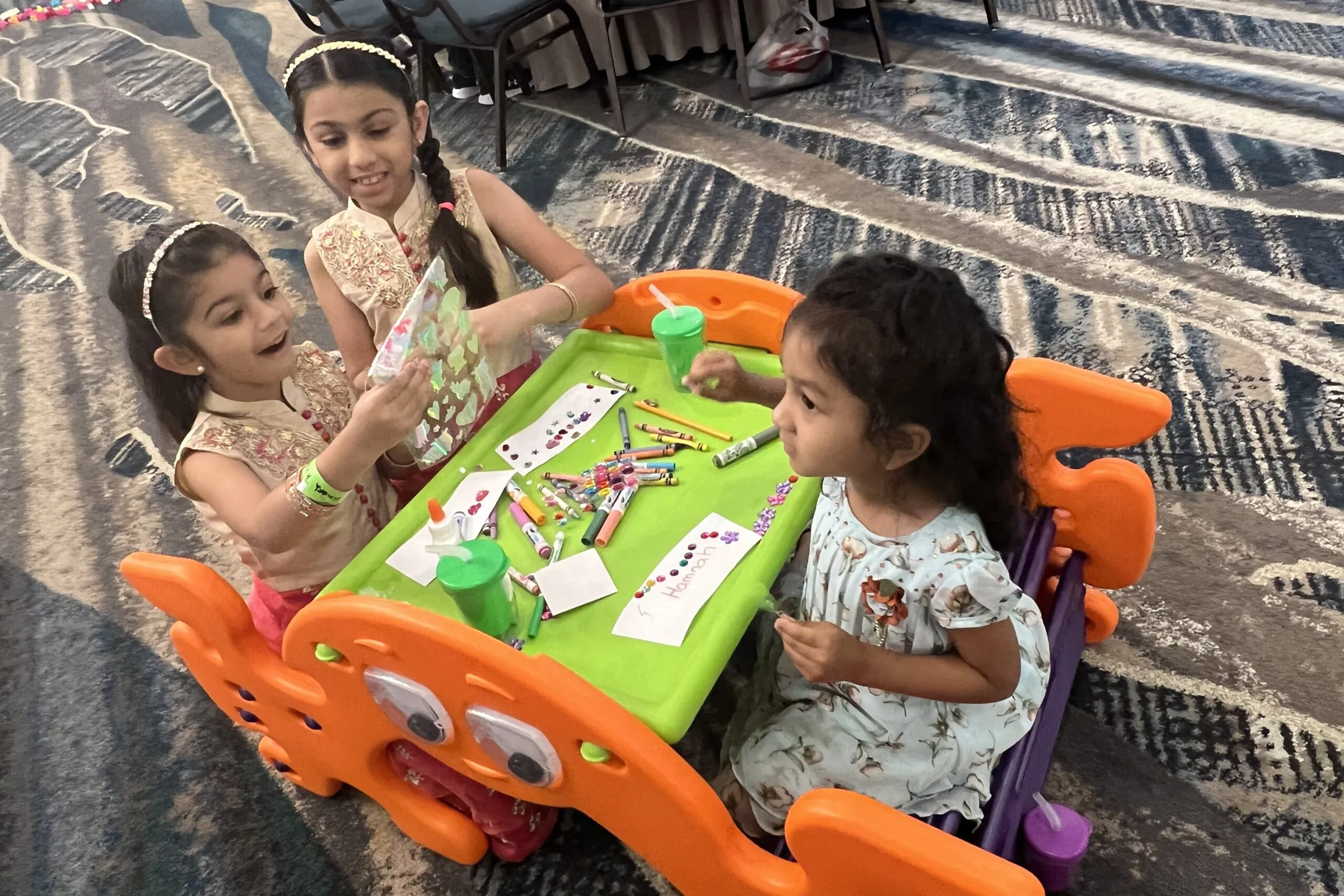 Children crafting together at a Tootles kids' activity table during an event childcare session